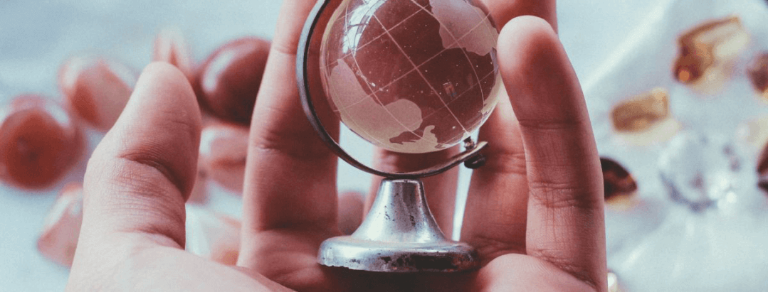 person holding a glass world globe